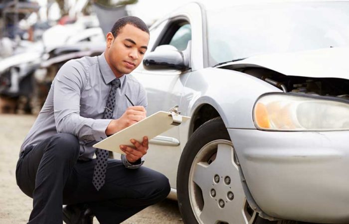 insurance adjuster inspecting damages to a car involved in an accident for blog post entitled How do I recover damages from an accident