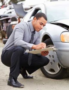 Close up of insurance adjuster inspecting damages to a car involved in an accident for blog post entitled How do I recover damages from an accident