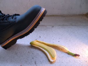 If you are injured on someone else’s property, the landowner may be liable for your injuries. Pictured: Person wearing boot is about to step on banana peel. 