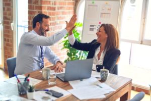 The best attorneys have the best client experience, going beyond just looking at wins and losses in the courtroom. Pictured: A man an a woman give high fives while sitting at a table.